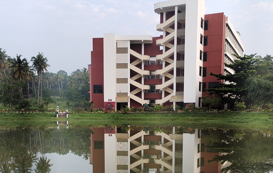Photo of a college building showing reflection from pond